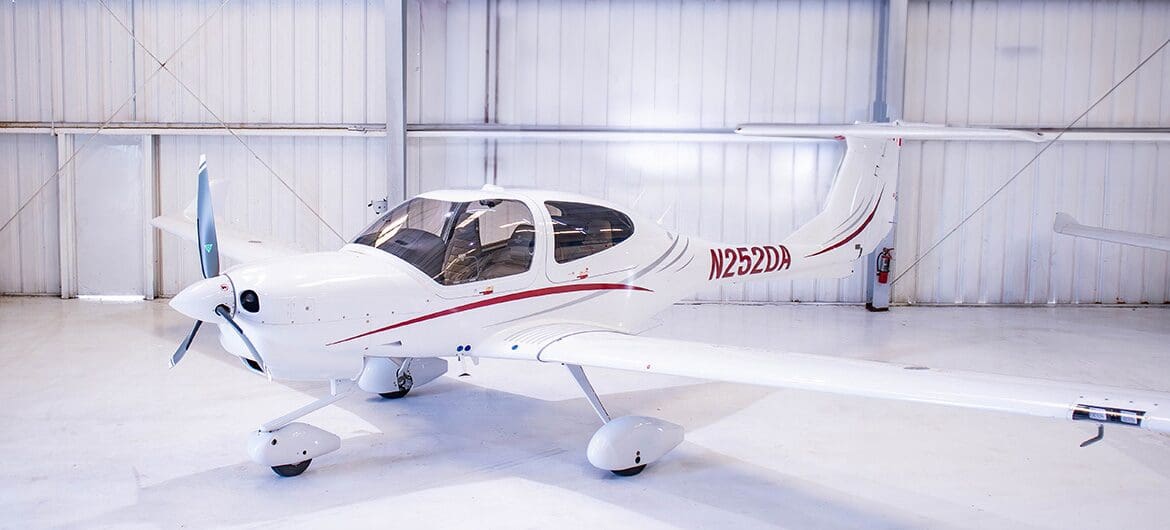 A small white airplane sitting in an airport hangar.