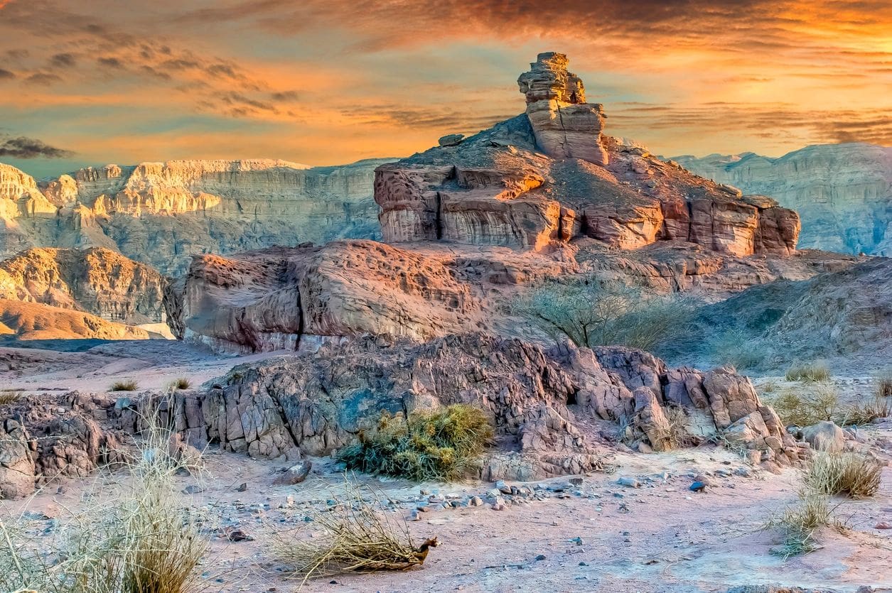 A painting of a desert landscape with mountains in the background.